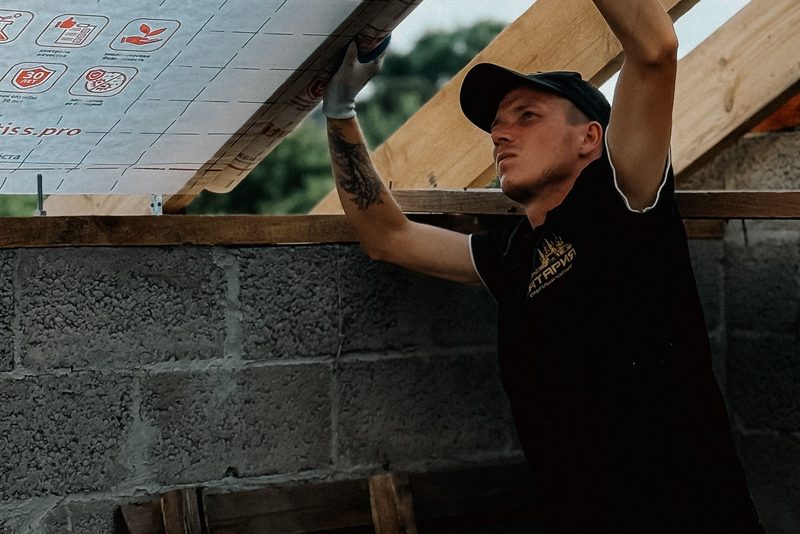 Pokrývač pod pojistnou fólií na krokvích při výměně krytiny